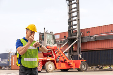 Caucasian engineer standing in front of Reach stacker vehicle in shipping yard. Inspector, dock...