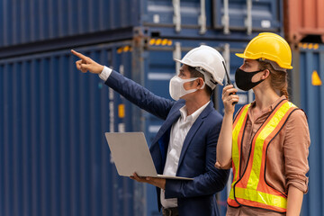 Female engineer using radio to command transportation. Inspector or businessman talking with dock worker and used laptop checking cargo freight container in shipping yard. Concept of logistics.