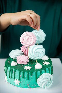 A Soft Green Birthday Cake Decorated With Pink And Blue Meringues