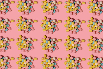 Food pattern. Repeating heap of bright marshmallows on a pink background. Multicolored marshmallows on a pink background. Sugar concept.
