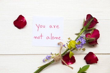 you are not alone message care handwriting with red rose flowers arrangement flat lay postcard...