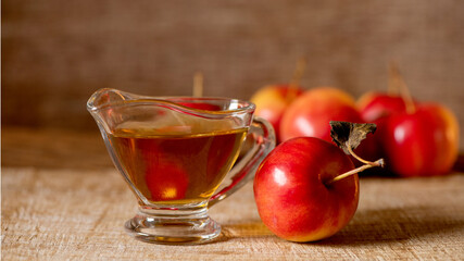 Apple cider vinegar in the glass and apple on a natural background.