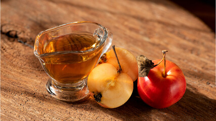 Apple cider vinegar in the glass and apple on a natural background.