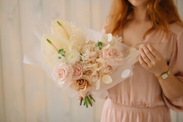 young woman florist in a pink dress with red hair holds a wedding bouquet of flowers roses