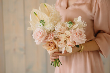 young woman florist in a pink dress with red hair holds a wedding bouquet of flowers roses