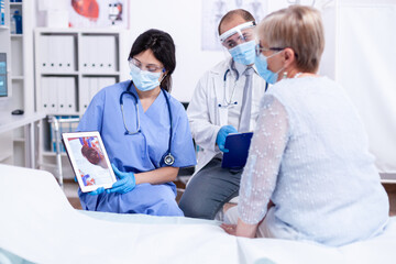 Cartdiologist telling senior woman what's wrong with her coronary artery during consulation in...