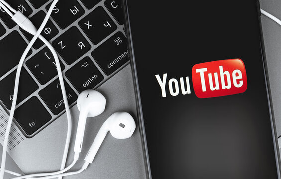 YouTube logo on the screen smartphone and Earpods closeup background. YouTube is a free video sharing application that anyone can watch. Moscow, Russia - June 28, 2020