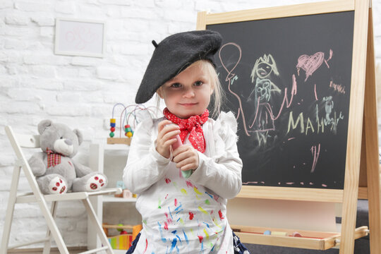 Indoor portrait of adorable 3 years old girl dressed up as a painter