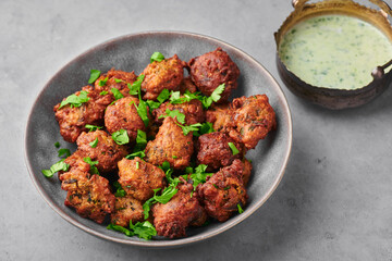 Veg Pakora in gray bowl on concrete table top. Pakoda is indian cuisine appetizer deep fried dish. Asian food and meal