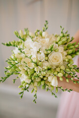 young woman florist in a pink dress with red hair holds a wedding bouquet of flowers roses