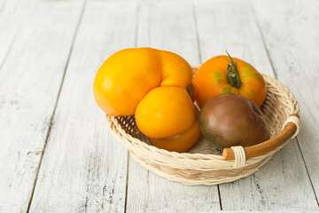 Yellow tomatoes on a white wooden background.