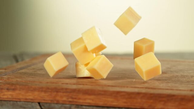 Super Slow Motion Shot of Cheese Chunks Falling on Wooden Board at 1000 fps.
