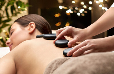 wellness, beauty and bodycare concept - close up of woman having hot stone massage at spa over...