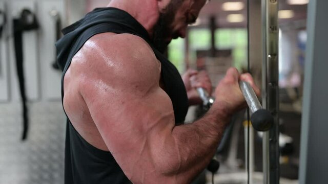 strong young bearded man athlete lifting heavy weight using exercise equipment indoors gym during sport workout biceps training shouting with effort