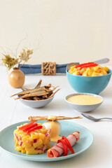 Henri Egg, tasty brunch or snack. Boiled eggs and smoked sprats fish with mayonnaise, ham and potato salad. White wooden table, no people.
