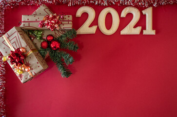 Christmas presents and ornaments on a red background. 2021 in wooden numbers . Copy space