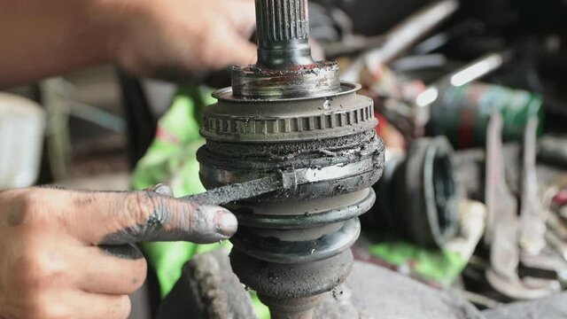Car Mechanic or Auto Mechanic Removing Outer Drive Shaft Rubber Boot Band in Zoom View