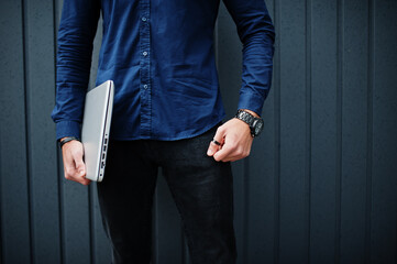 Close up photo of man hands with laptop against steel wall.