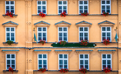 Vintage facade with windows and red flowers in Krumlov