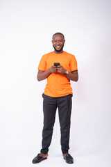 smiling african man texting on his phone standing on a white background