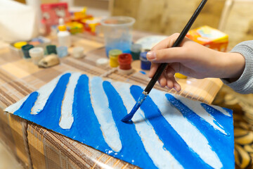the girl draws blue gouache cardboard, makes a abstract background, sits in the home kitchen