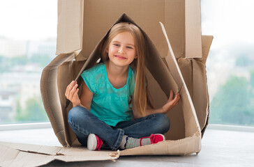 Beautiful little blonde girl playing in shipping box