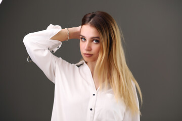 beautiful blonde in a white shirt on a gray background