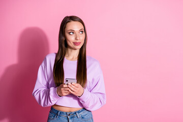 Portrait of curious minded creative girl blogger use smartphone look copyspace think thoughts decide type social network news wear stylish trendy jumper isolated pastel color background