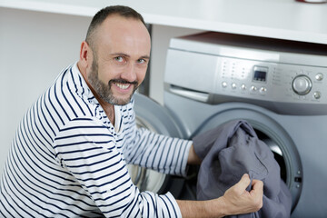 man loading clothes into washing machine