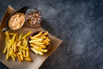 French fries with sauce and drink laid on pergament paper