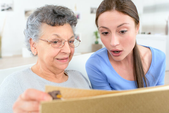 woman and senior woman with photo album at home