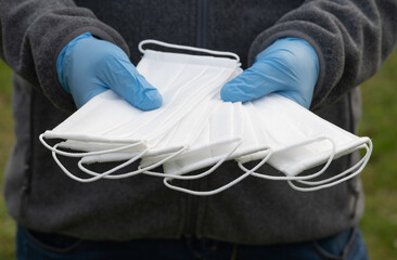 gloved hands holding several masks