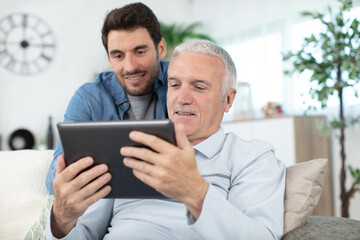 hipster son and his senior father with tablet at home