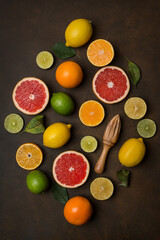 Orange, lemon, grapefruit, lime, mandarin different citrus fruits on a dark brown background, top view.