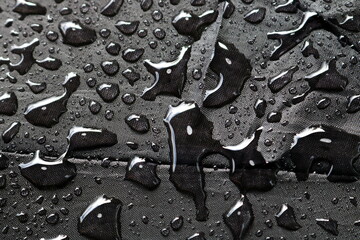 
Rain water droplets on black fiber waterproof fabric. Black background