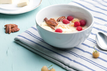 Delicious amaranth with butter, fresh raspberries and banana, pecans and almond chips. Plant-based breakfast. Healthy colorful gluten free concept.