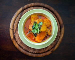 Chicken curry in a green bowl on a wooden base background.