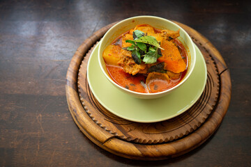 Chicken curry in a green bowl on a wooden base background.