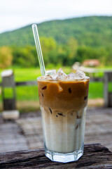 Iced coffee latte on a wooden table at the cafe behind a beautiful mountain view