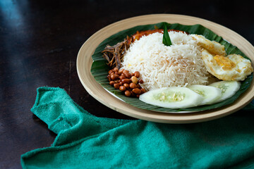 Traditonal Malaysia Asian food Nasi Lemak on a banana leaf in a wooden bamboo plate.