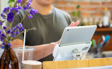 The counter staff use the tablet to accept orders and accept payments from customers in the coffee shop: the modern concept of a coffee shop business, food and beverages.