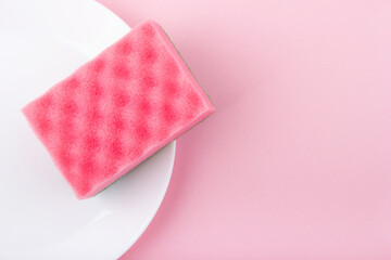 Pink sponge on the pink background. Top view. Cleaning and housewashing concept.