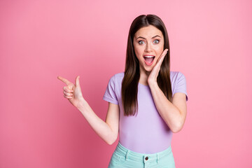 Photo of funny pretty shocked lady direct finger side empty space show novelty sale shopping season open mouth wear casual violet t-shirt teal pants isolated pink pastel color background
