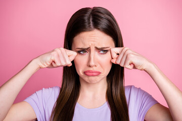 Fototapeta premium I want home. Closeup photo of displeased crying lady wiping tears arms fingers upset sad gloomy miss parents family wear purple t-shirt isolated pastel pink color background