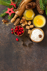 Baking winter. Ingredients for Christmas baking - cocoa, cranberries, spices, nuts, flour and eggs  on a rustic wooden table. Top view flat lay background. Copy space.