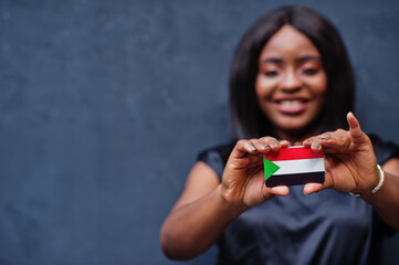 African woman hold small Sudan flag in hands.