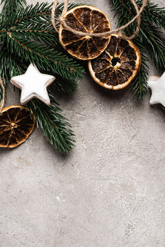 Top view of dried orange slices, cookies and pine branch on textured background