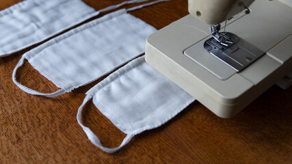 A protective gauze bandages for the face close to a sewing machine. Basic protection against coronavirus, COVID-19, infections and dust at home. Do-it-yourself face mask at home.