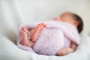 New born baby girl sleeps at home, legs close up. Cute little kid's portrait