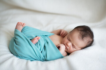 New born baby girl sleeps at home and smiling in a dream. Cute little kid's portrait
